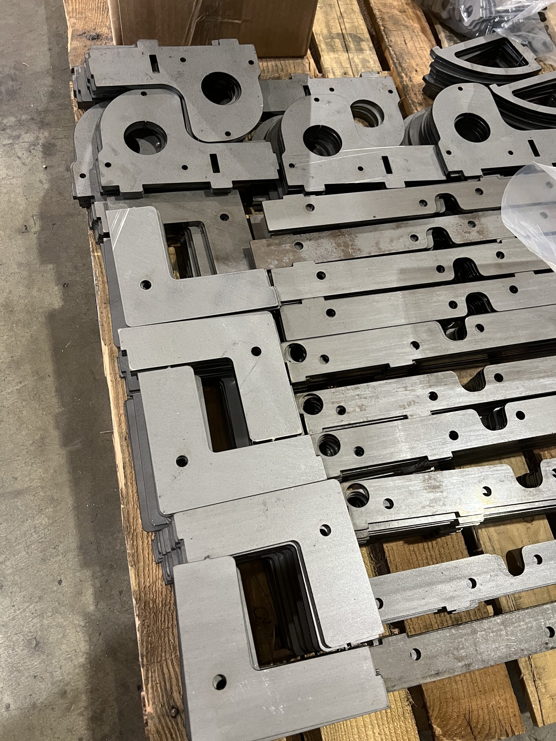 Stack of precision laser-cut metal components neatly arranged on a pallet, ready for assembly or further fabrication.